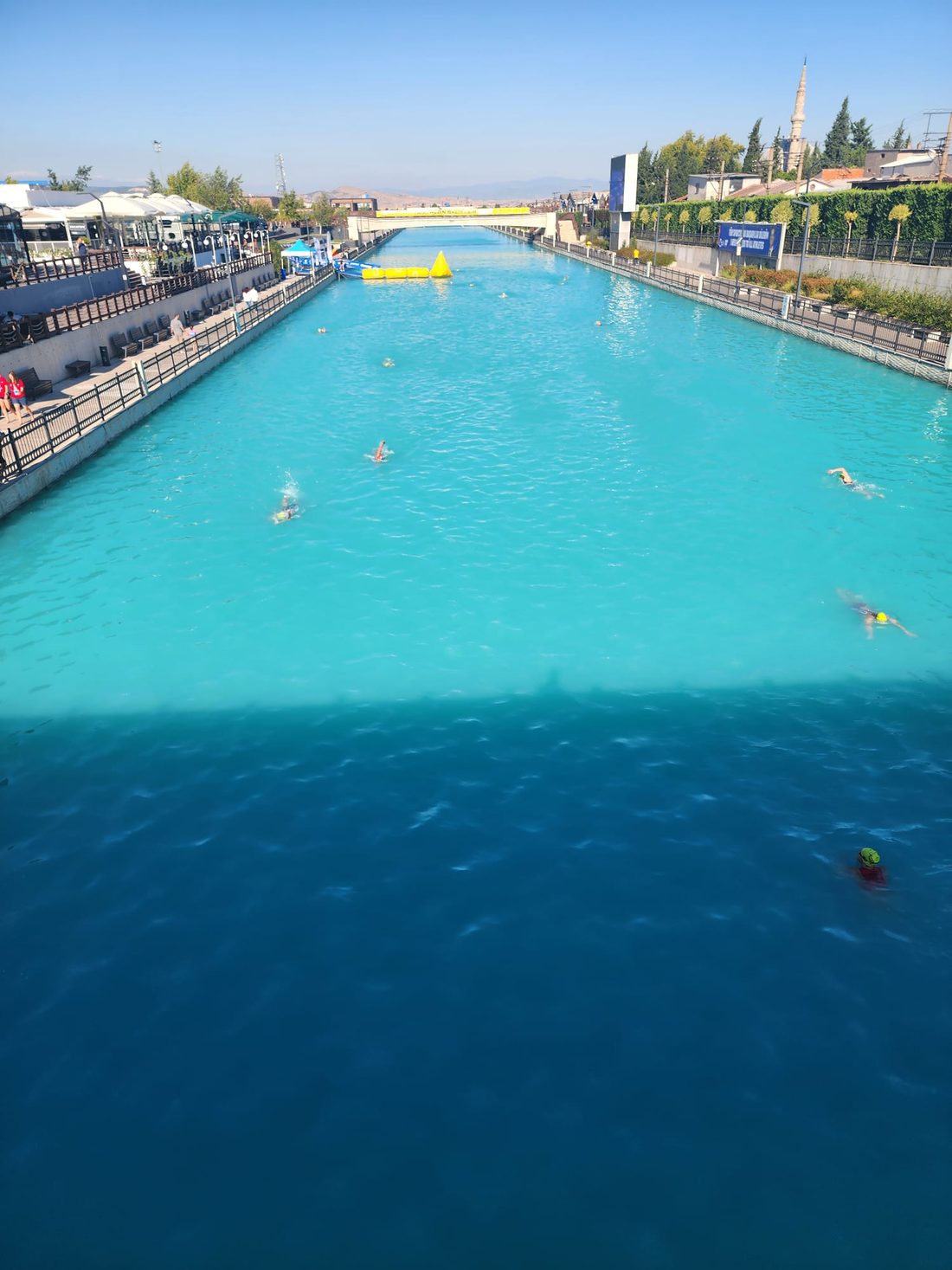 Triathleten schwimmen während der Schwimmstrecke im Kanal; Zuschauer an den Ufern